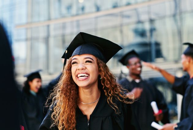 girl at graduation smiling, pictured wearing hat and gown