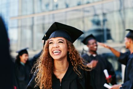 girl at graduation smiling, pictured wearing hat and gown